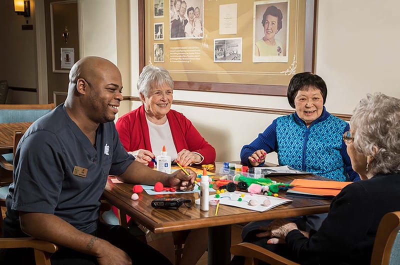 10 Wilmington Place Memory Care residents smile while doing a craft together 
