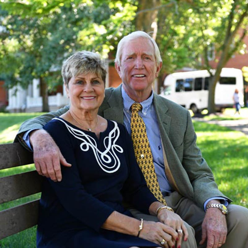 Barry Humphries the owner of 10 Wilmington Place and his wife smile and sit on a bench outside on the beautiful grounds in Dayton, Ohio