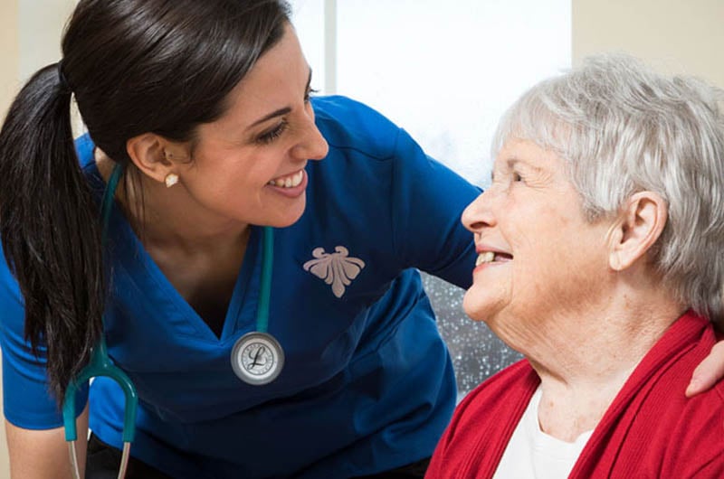 skilled nurse smiles at a memory care resident who smiles back