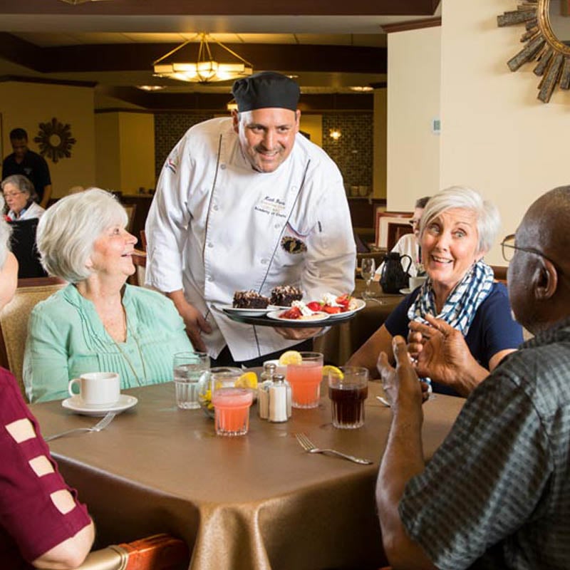 the chef at 10 wilmington place offering dessert to a group of residents in the dining area