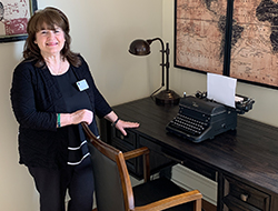 Tammy McVicar standing next to a desk with an antique typewriter in the Josephine Memory Care Center