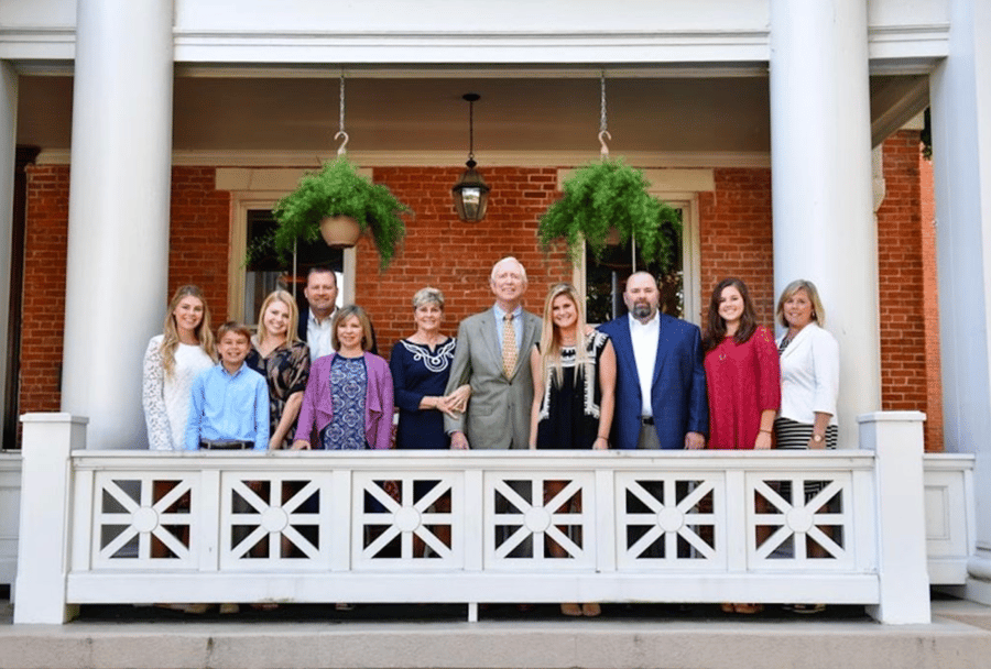 A multi-generational family smiles on a front porch together