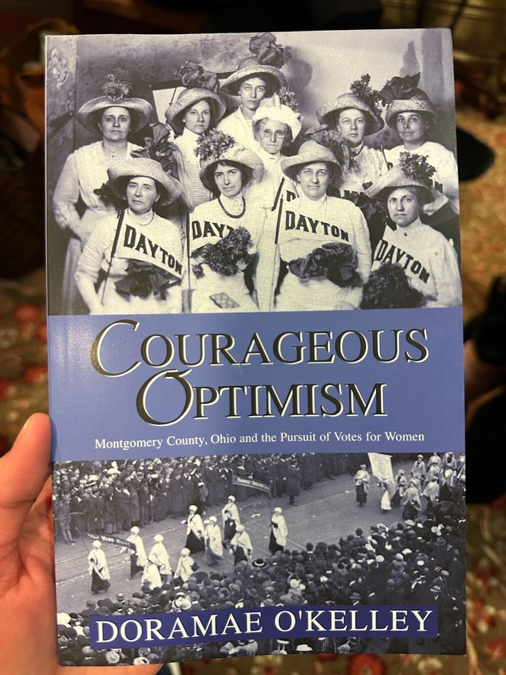 A book called Courageous Optimism by DoraMae O'Kelley is shown